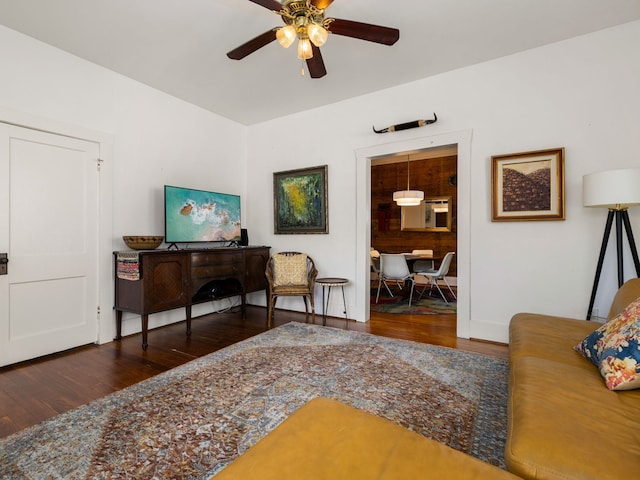 living room featuring dark wood-type flooring and ceiling fan