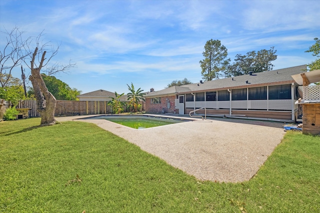 rear view of house featuring a fenced in pool and a lawn