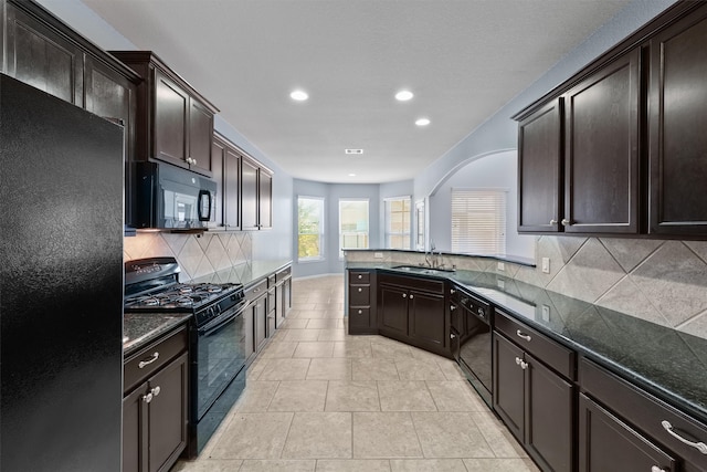 kitchen featuring dark brown cabinets, sink, tasteful backsplash, and black appliances