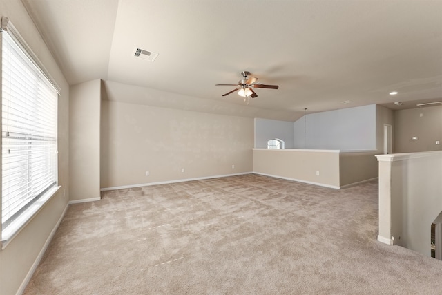 spare room featuring ceiling fan, light colored carpet, a healthy amount of sunlight, and vaulted ceiling