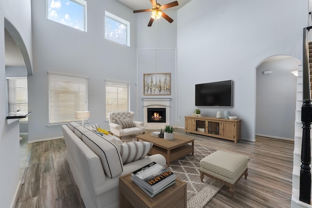 living room with a high ceiling, hardwood / wood-style flooring, and ceiling fan