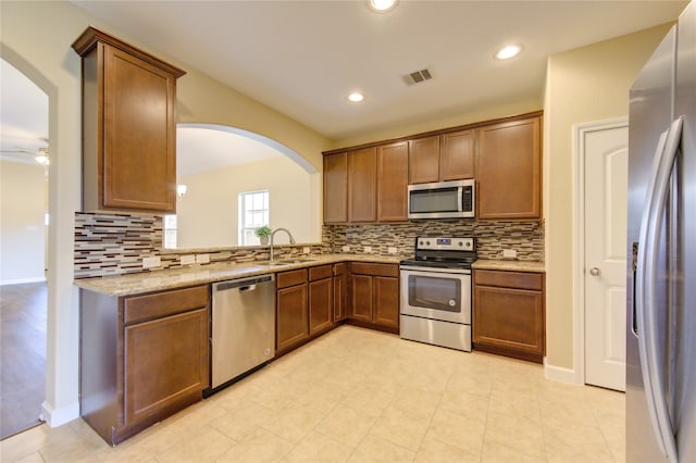 kitchen featuring sink, light stone counters, tasteful backsplash, appliances with stainless steel finishes, and ornamental molding