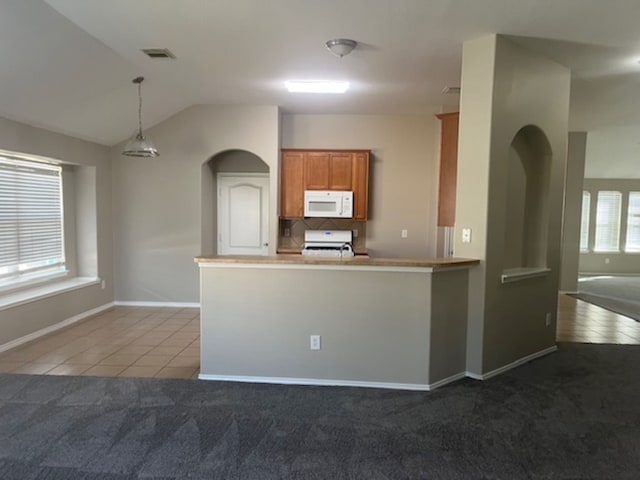 kitchen with lofted ceiling, light carpet, kitchen peninsula, decorative light fixtures, and stove