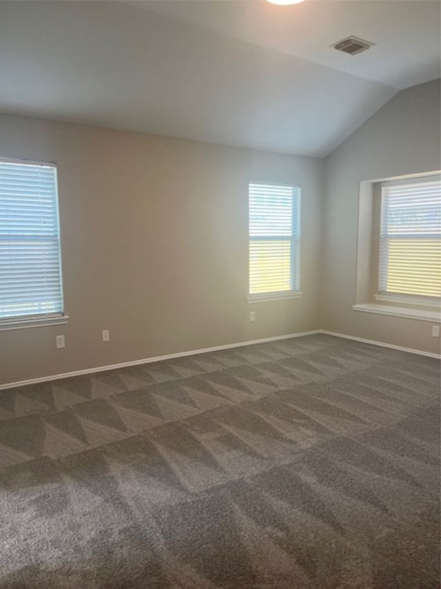 carpeted empty room featuring vaulted ceiling