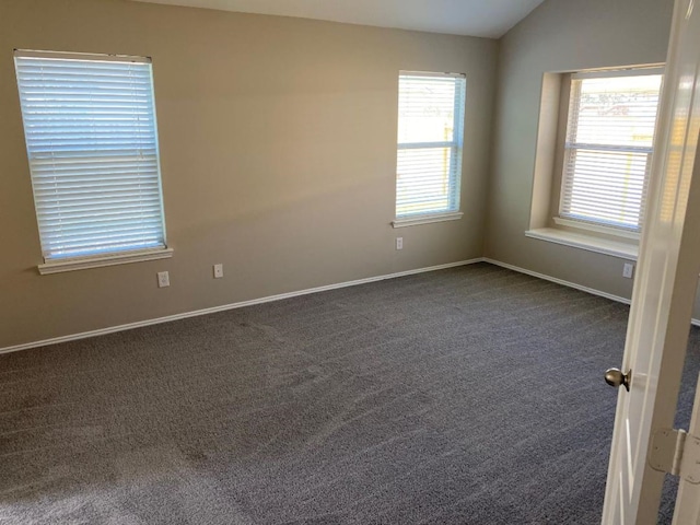 carpeted spare room featuring vaulted ceiling and plenty of natural light