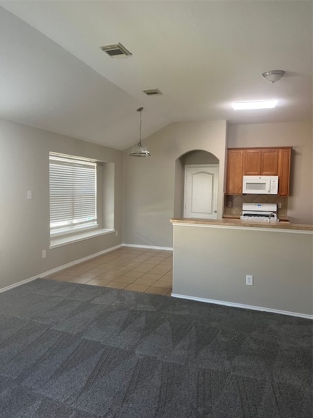 kitchen featuring vaulted ceiling, decorative light fixtures, light colored carpet, and range