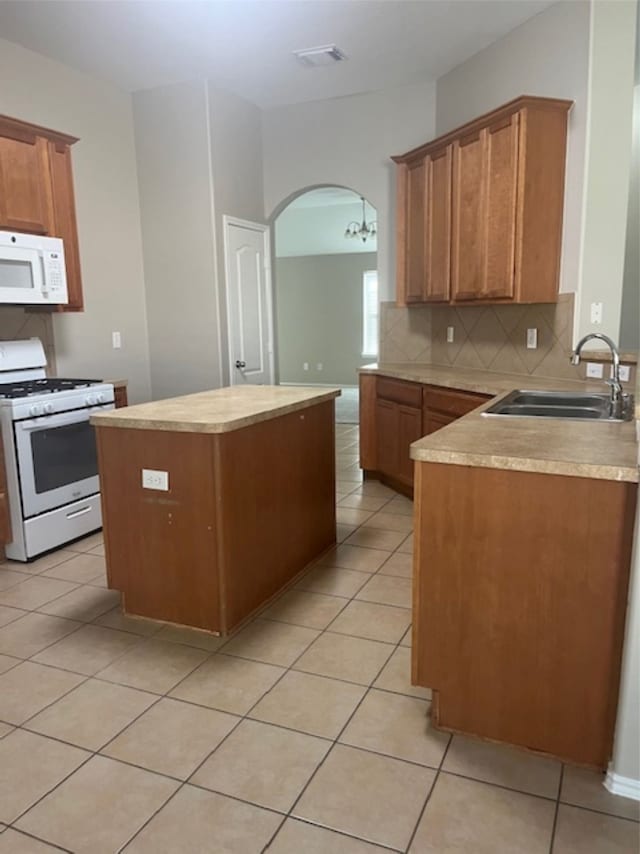 kitchen featuring tasteful backsplash, light tile patterned floors, sink, a center island, and white appliances