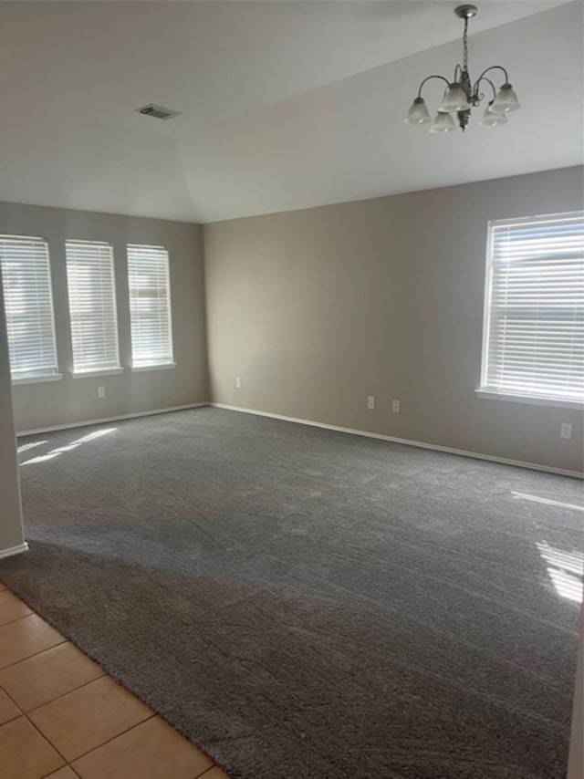 empty room with carpet, lofted ceiling, a chandelier, and plenty of natural light