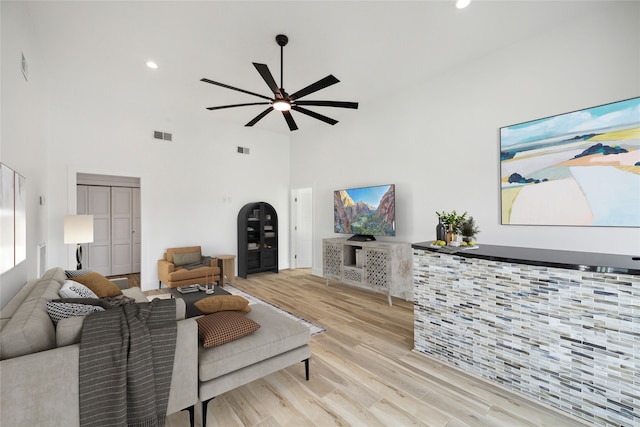 living room featuring ceiling fan, light hardwood / wood-style flooring, and a high ceiling