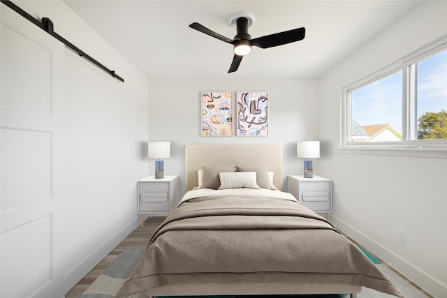 bedroom featuring a barn door, hardwood / wood-style flooring, and ceiling fan