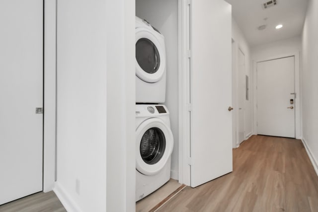 clothes washing area featuring light hardwood / wood-style flooring and stacked washer and dryer