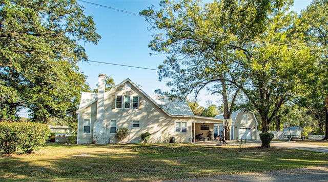 rear view of property with an outdoor structure, a garage, and a lawn