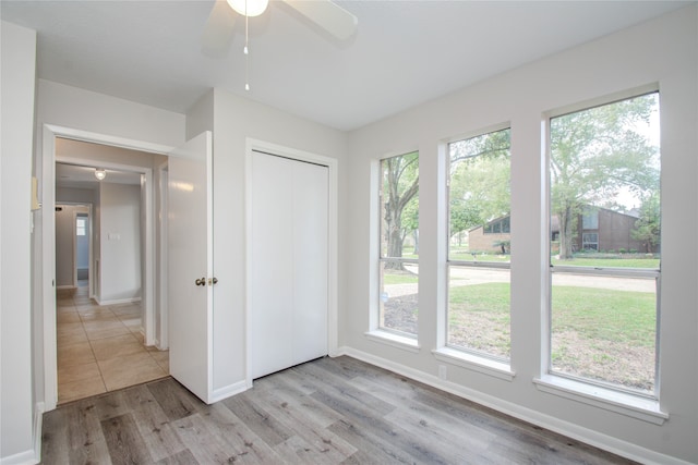 unfurnished bedroom with multiple windows, light wood-type flooring, and ceiling fan