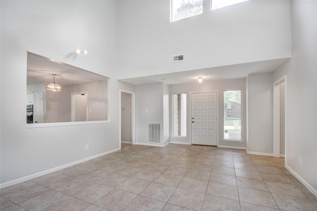 tiled entryway featuring a high ceiling and an inviting chandelier