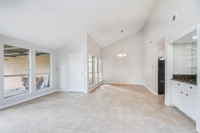 interior space featuring pendant lighting, white cabinets, high vaulted ceiling, light tile patterned floors, and an inviting chandelier