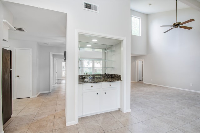 kitchen with white cabinets, dark stone countertops, light tile patterned flooring, and plenty of natural light