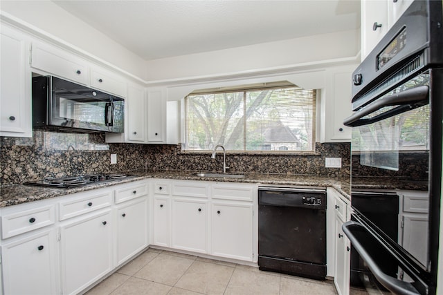 kitchen with light tile patterned floors, white cabinetry, dark stone countertops, black appliances, and sink