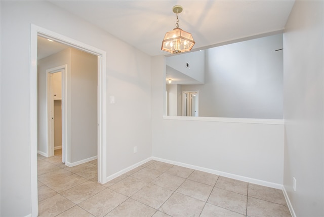 tiled spare room with a chandelier