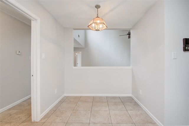 unfurnished dining area featuring light tile patterned flooring and ceiling fan with notable chandelier