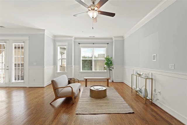 sitting room featuring french doors, crown molding, wood-type flooring, and ceiling fan