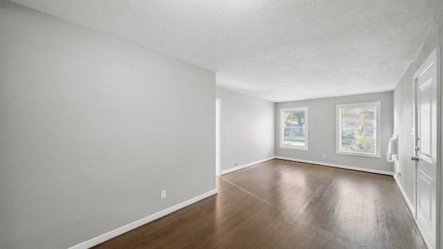 unfurnished room with a textured ceiling and dark hardwood / wood-style floors