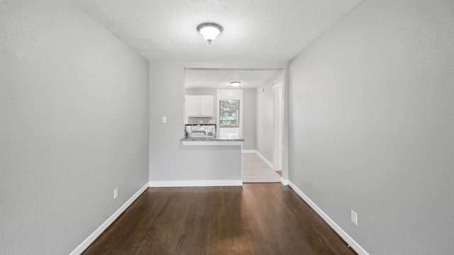 corridor featuring a textured ceiling and dark hardwood / wood-style flooring