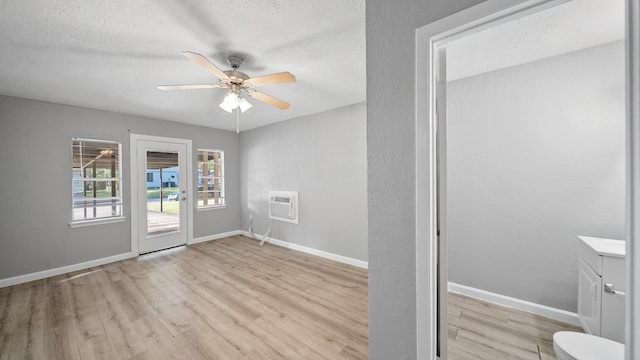 doorway featuring light hardwood / wood-style floors, a textured ceiling, a wall mounted AC, and ceiling fan