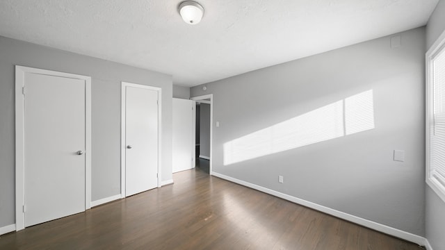 unfurnished bedroom with dark hardwood / wood-style floors and a textured ceiling