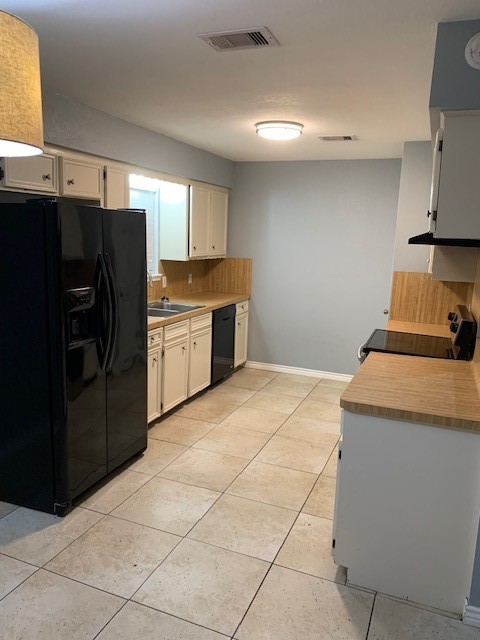 kitchen featuring sink, black appliances, decorative backsplash, and light tile patterned floors