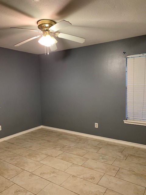 empty room with ceiling fan and a textured ceiling