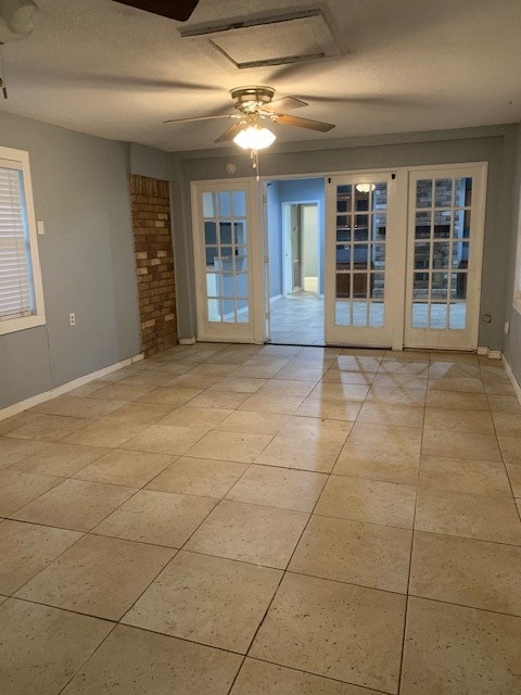 empty room featuring french doors, a textured ceiling, light tile patterned floors, and ceiling fan