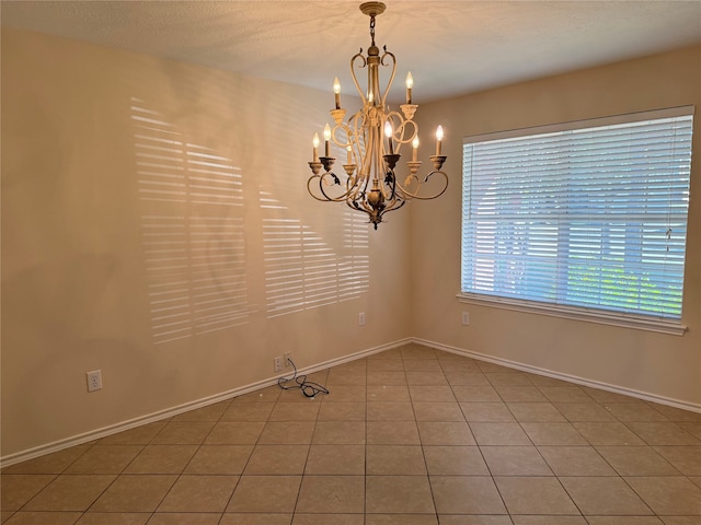 tiled empty room featuring a notable chandelier