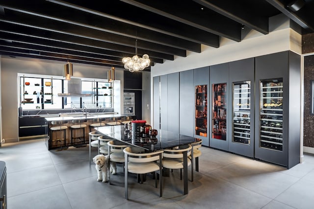 dining space with beam ceiling, a chandelier, and bar