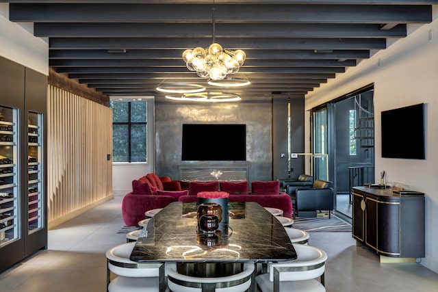 dining area with a notable chandelier, a healthy amount of sunlight, beam ceiling, and concrete floors