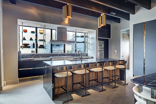 kitchen featuring a breakfast bar area, extractor fan, beamed ceiling, sink, and a center island