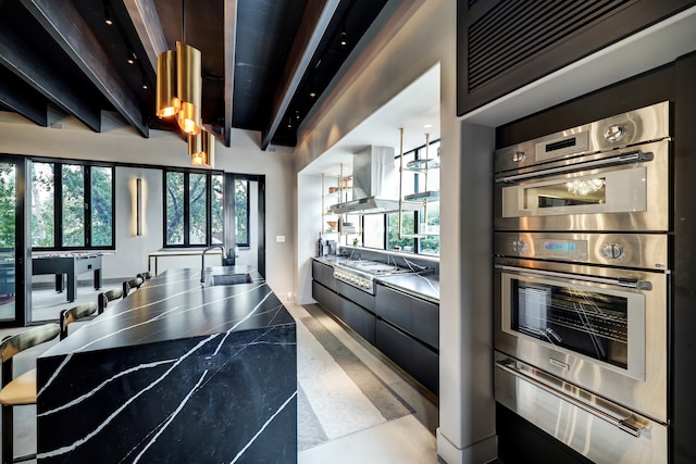 kitchen featuring stainless steel appliances, beamed ceiling, sink, and a wealth of natural light