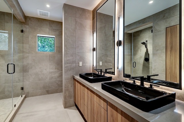 bathroom featuring a shower with door, vanity, tile patterned flooring, and tile walls