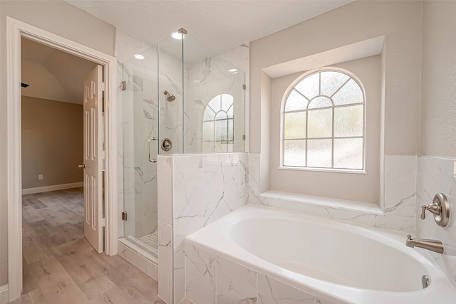 bathroom with hardwood / wood-style flooring and shower with separate bathtub