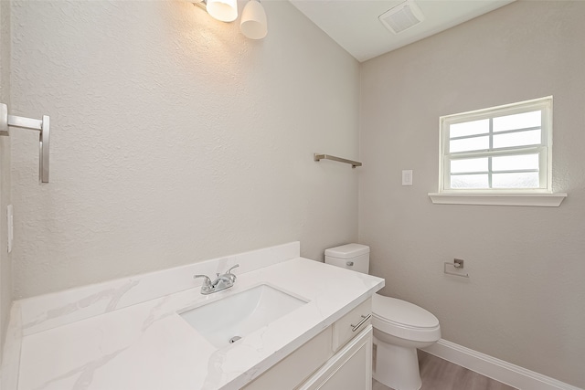 bathroom with vanity, toilet, and hardwood / wood-style floors