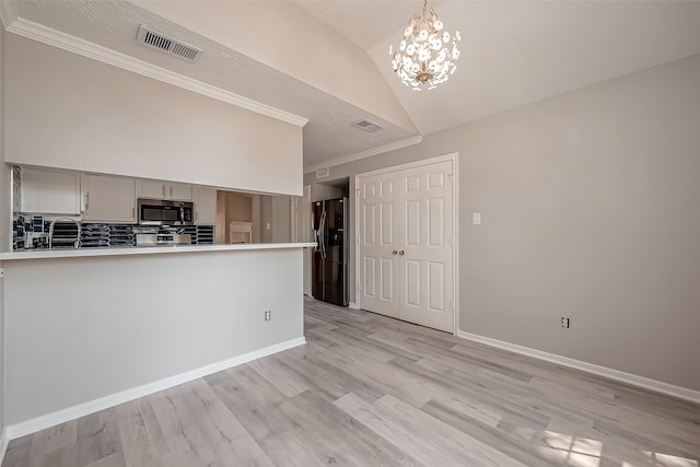 kitchen featuring black fridge, an inviting chandelier, light wood-type flooring, vaulted ceiling, and ornamental molding