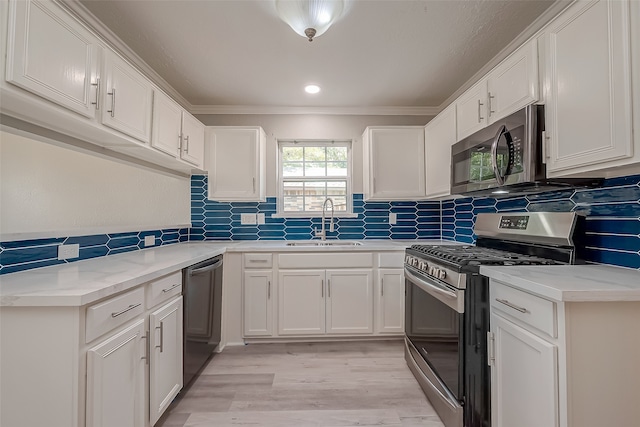 kitchen with ornamental molding, sink, white cabinets, appliances with stainless steel finishes, and light hardwood / wood-style floors