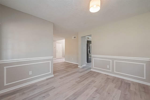 spare room featuring a textured ceiling and light hardwood / wood-style flooring