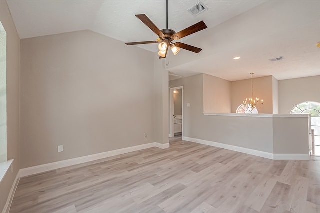 empty room featuring vaulted ceiling, light hardwood / wood-style flooring, a textured ceiling, and ceiling fan with notable chandelier