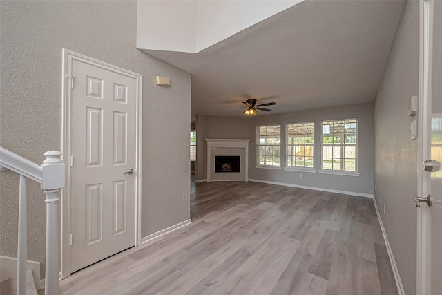 unfurnished living room featuring light hardwood / wood-style floors, a fireplace, and ceiling fan