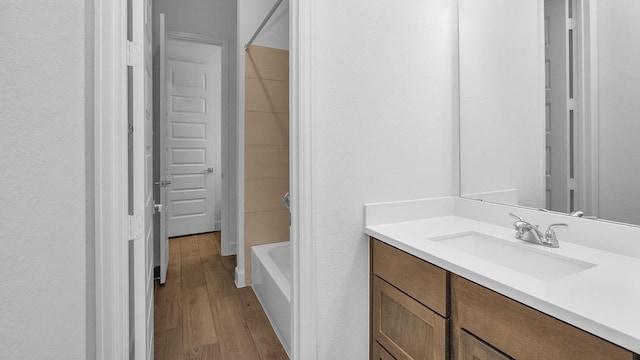 bathroom featuring hardwood / wood-style flooring, vanity, and  shower combination