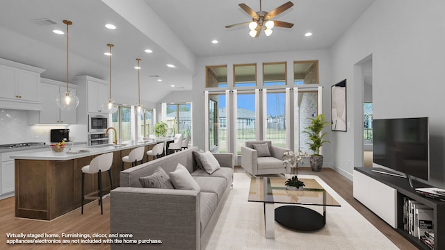 living room featuring hardwood / wood-style flooring, high vaulted ceiling, and ceiling fan