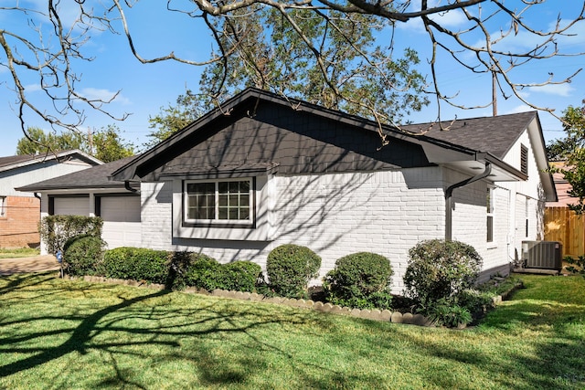 view of side of property featuring a lawn, a garage, and central AC unit