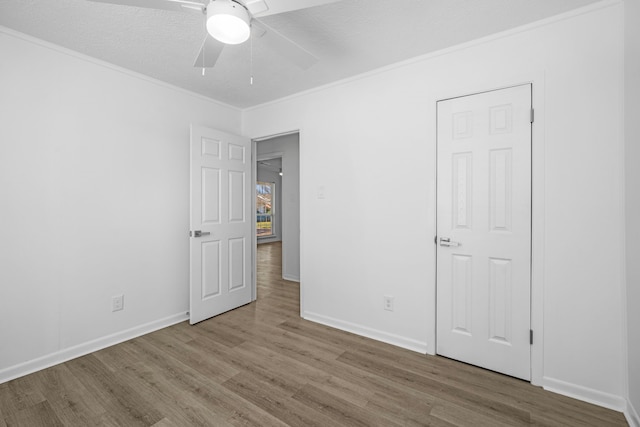 unfurnished bedroom featuring light hardwood / wood-style flooring, a textured ceiling, crown molding, and ceiling fan