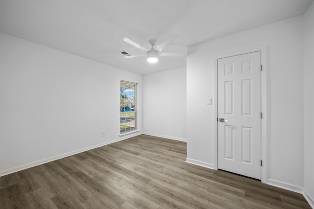 empty room with ceiling fan, a textured ceiling, and hardwood / wood-style floors