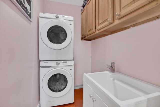 clothes washing area featuring stacked washer / dryer and cabinets